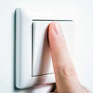 Schaltzyklen: Mann bet&auml;tigt Lichtschalter mit Zeigefinge